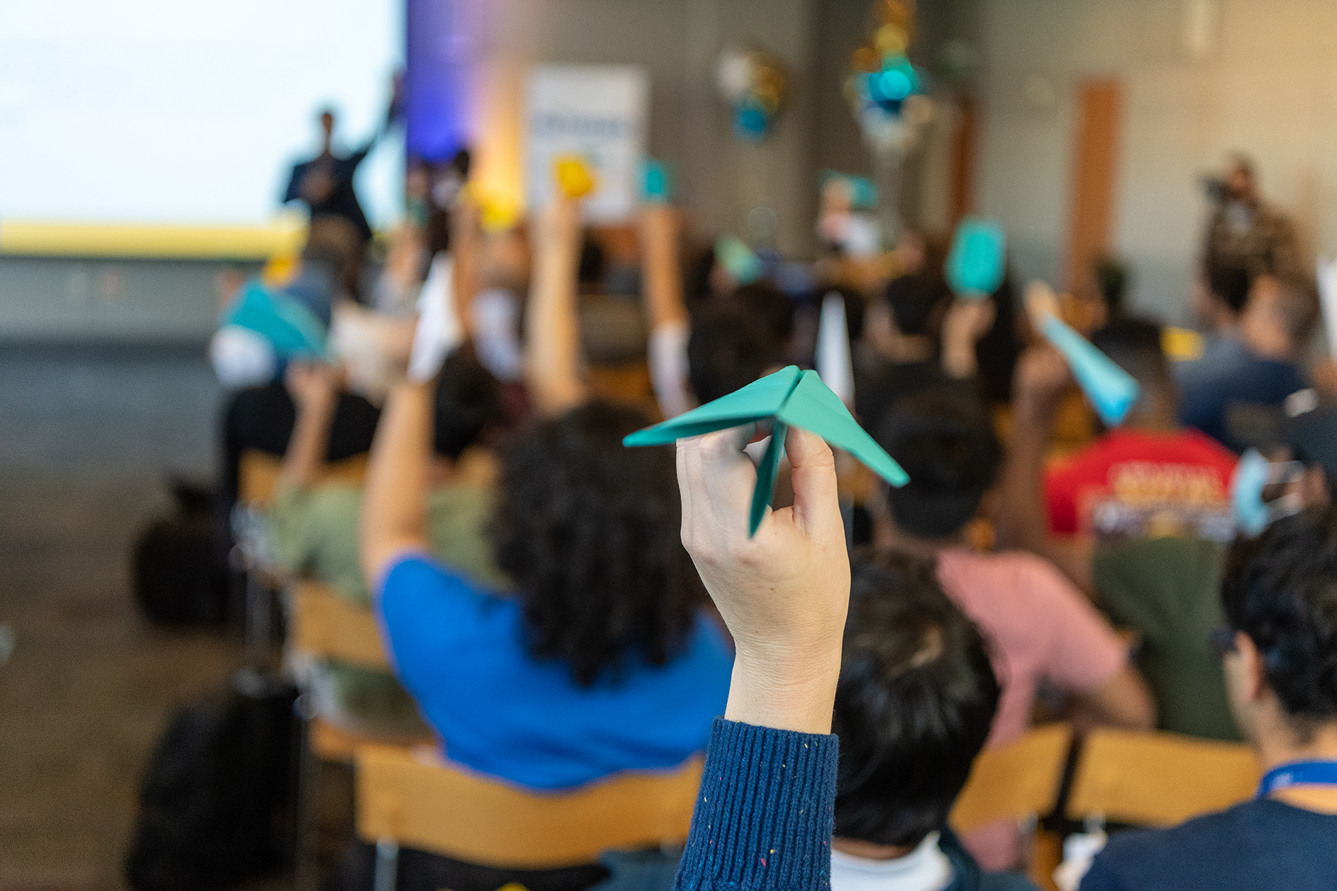 Students holding up paper airplanes